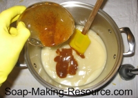 pouring annatto seed powder into soap