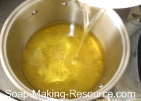 Pouring lye solution into the oils Pouring lye solution into the oils